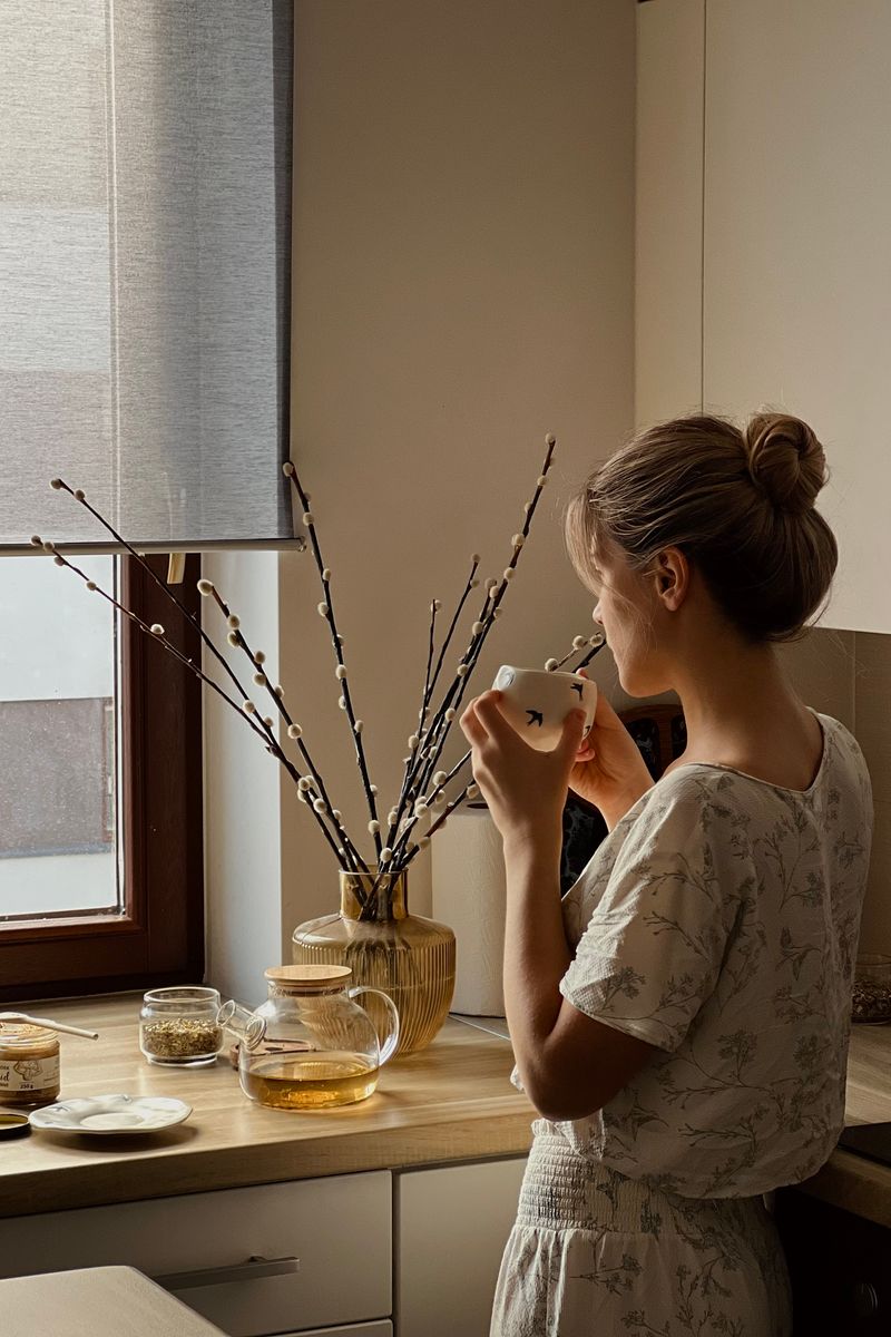 A woman sitting calmly by a window with a cup of tea